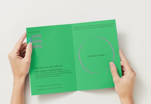 Green booklet held open by hands on a white background